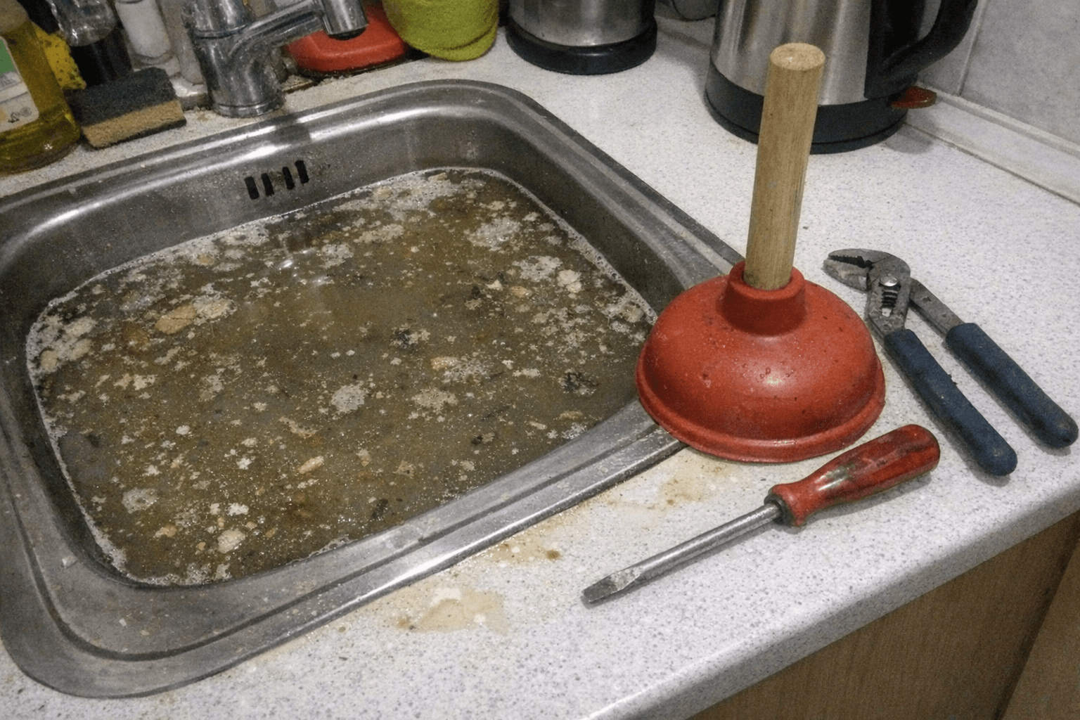 Einsatzkraft beseitigt einen Rückstau an einer verstopften Küchenspüle