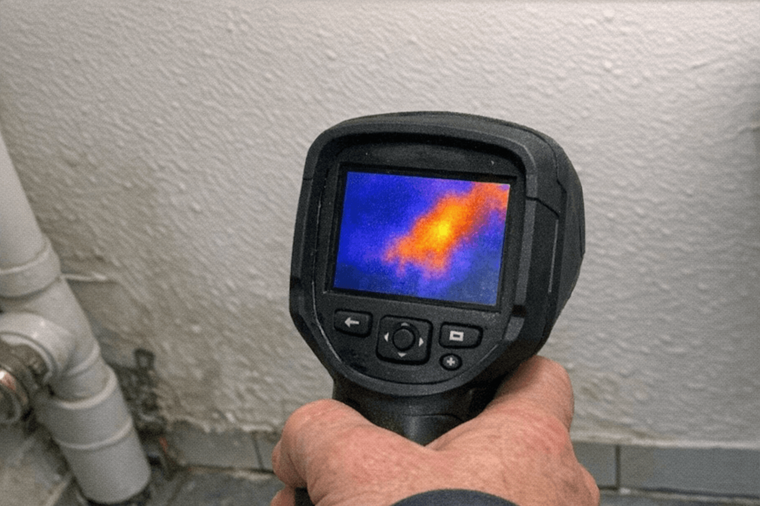 Messgerät an einer Badezimmerwand zur punktgenauen Suche nach einer undichten Leitung